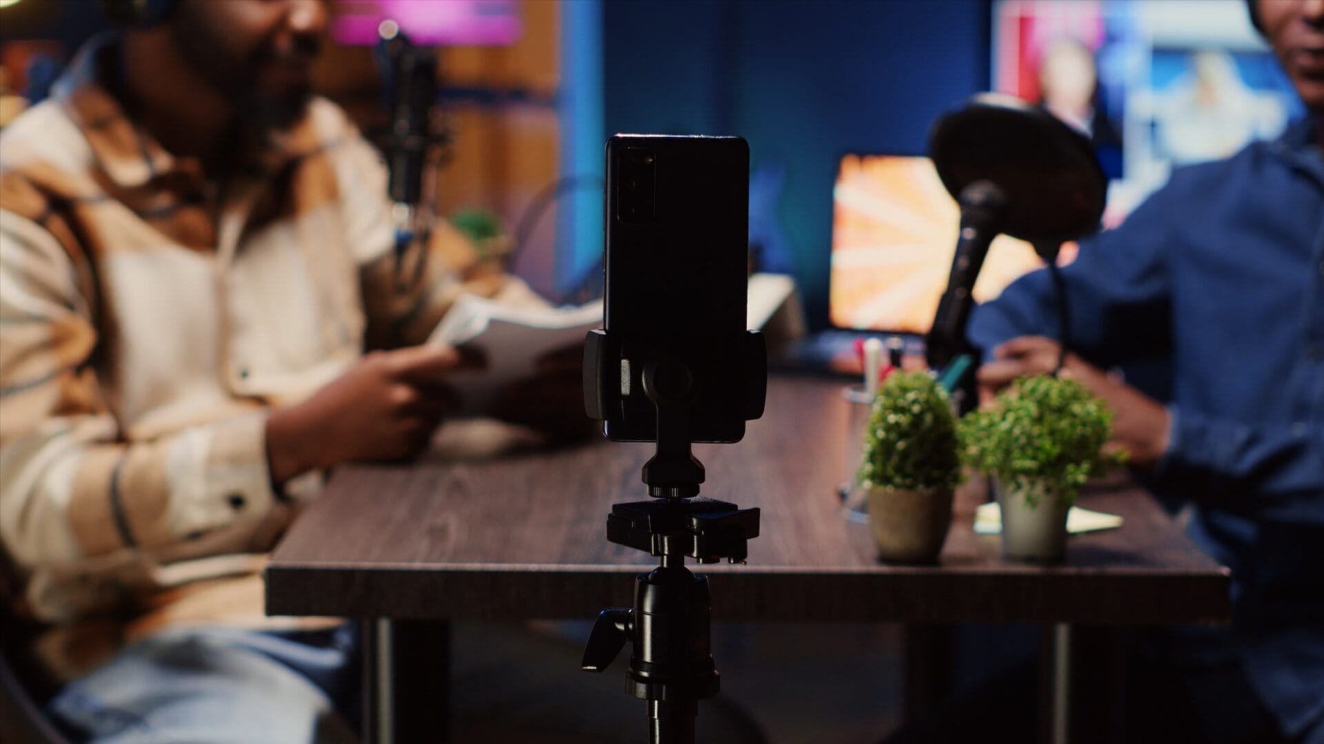 Smartphone mounted on tripod recording a podcast guest in a studio setting, capturing authentic storytelling and influencer content creation for social media audiences.</p>
<p>